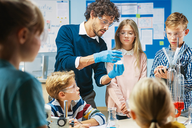 Ein Lehrer führt seiner Klasse ein Chemie-Experiment vor. 