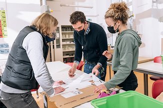 Drei Lehrkräfte schauen auf Baupläne für das Technikprojekt