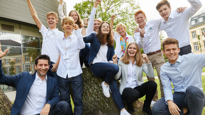 Eine Gruppe Schüler:innen und ein Lehrer jubeln. 