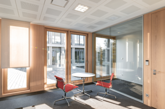 Ein moderner Büroraum mit großen Glasfenstern, eleganten Holzmöbeln und offenen Arbeitsbereichen, gestaltet von Kitzmann Architekten mit Heiner Leiska.
