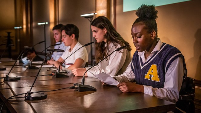 © House of Literature Hamburg Zu sehen sind vier Schüler:innen, die auf der Bühne an einem Tisch sitzen und vorlesen.