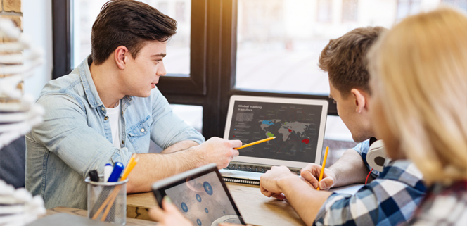 Drei Schüler:innen schauen auf einen Laptop, einer der Schüler zeigt auf eine digitale Karte. 