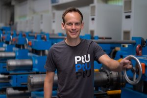 Lukas Kluy, Doktorand an der TU Darmstadt, steht an einer Maschine. 