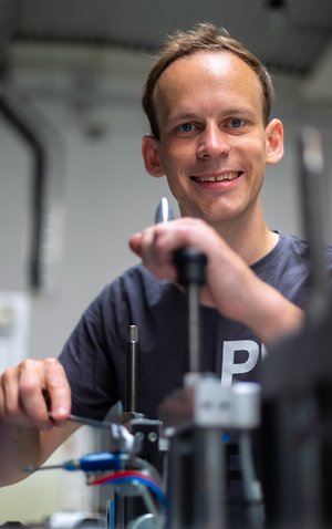 Lukas Kluy, Doktorand an der TU Darmstadt, steht an einer Maschine. 