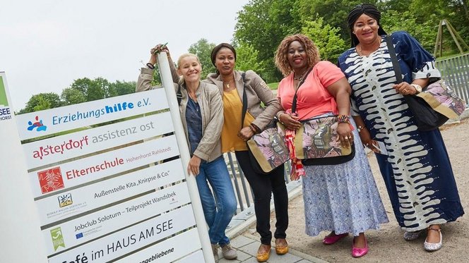 Stadtteilmütter aus Rahlstedt stehen vor einem Wegweiser zu sozialen Einrichtungen im Quartier