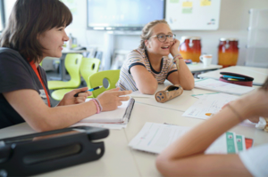 Drei Jugendliche sitzen an einem Tisch und überlegen.