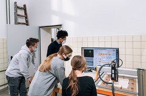 Vier Schüler:innen bedienen eine CNC-Fräse