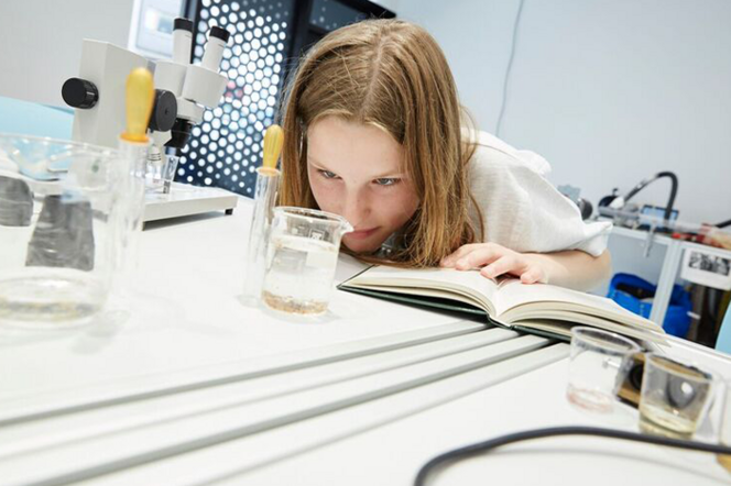 Mädchen schaut während eines Experiments in ein Reagenzglas. 