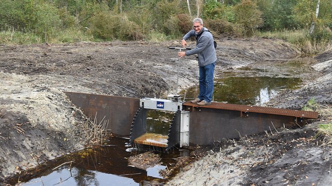 Herr Fuellhaas auf steht auf einem Kippwehr, das den Wasserstand auf regulieren kann. Er schließt die Schleuse, sodass das Wasser auf der entsprechenden Seite bleiben kann.