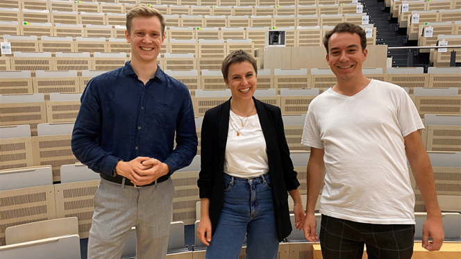 Drei Teilnehmende der Kooperation: Die drei Personen, zwei Journalisten und eine Wissenschaftlerin, stehen im Auditorium der TU Harburg und lachen in die Kamera.