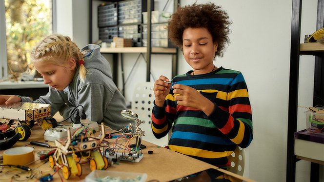 Ein Mädchen und ein Junge bauen eigene Fahrzeuge im Technikunterricht.