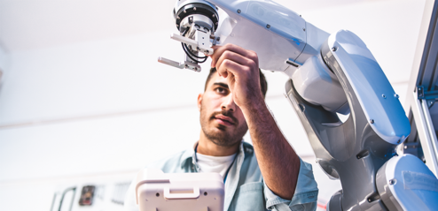 Ein Ingenieur stellt etwas an einem Roboter ein.