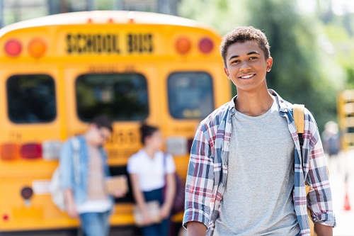 Ein Junge vor einem amerikanischen Schulbus